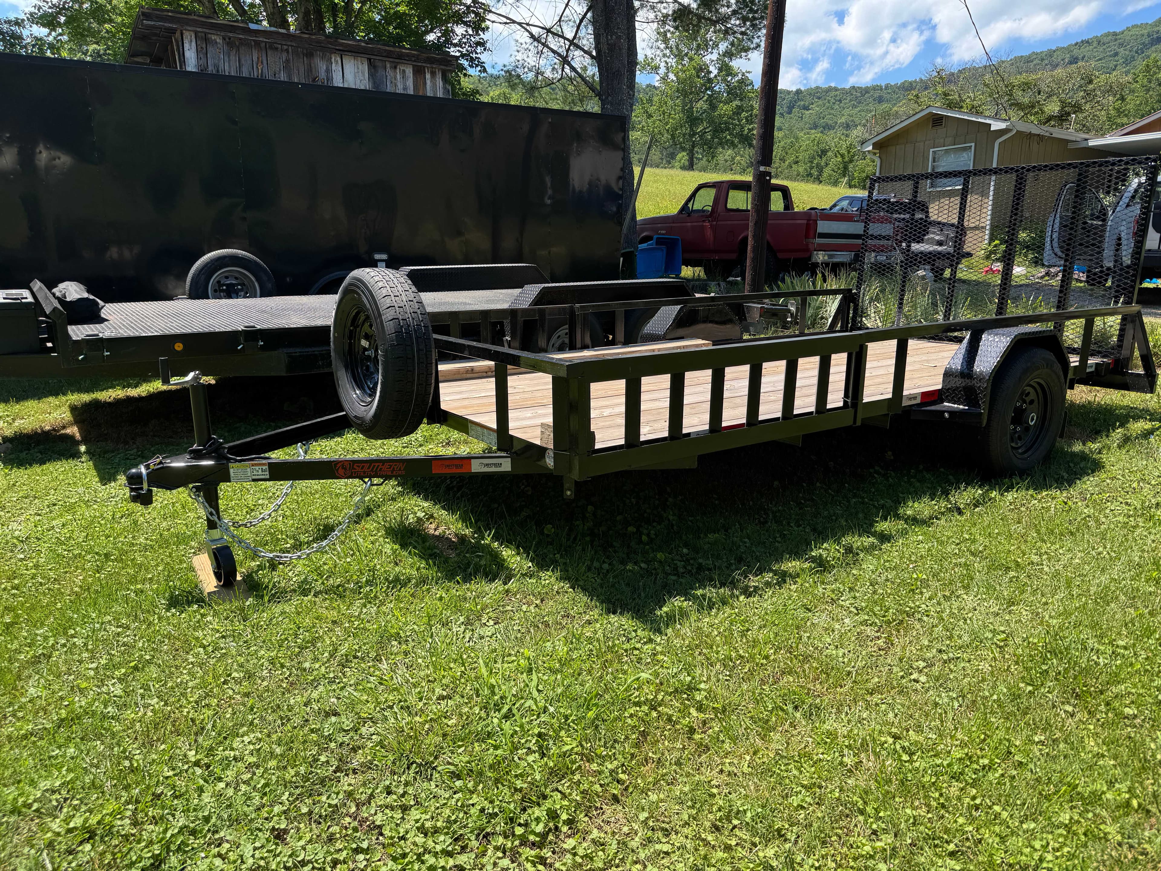 Utility trailer parked in a grassy yard with mountain scenery in the background